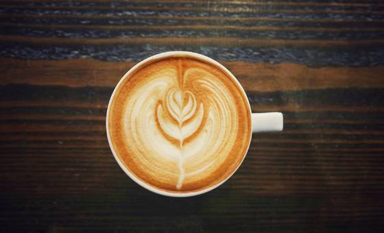 A capucino with a fancy swirly design in the foam that looks like a flower